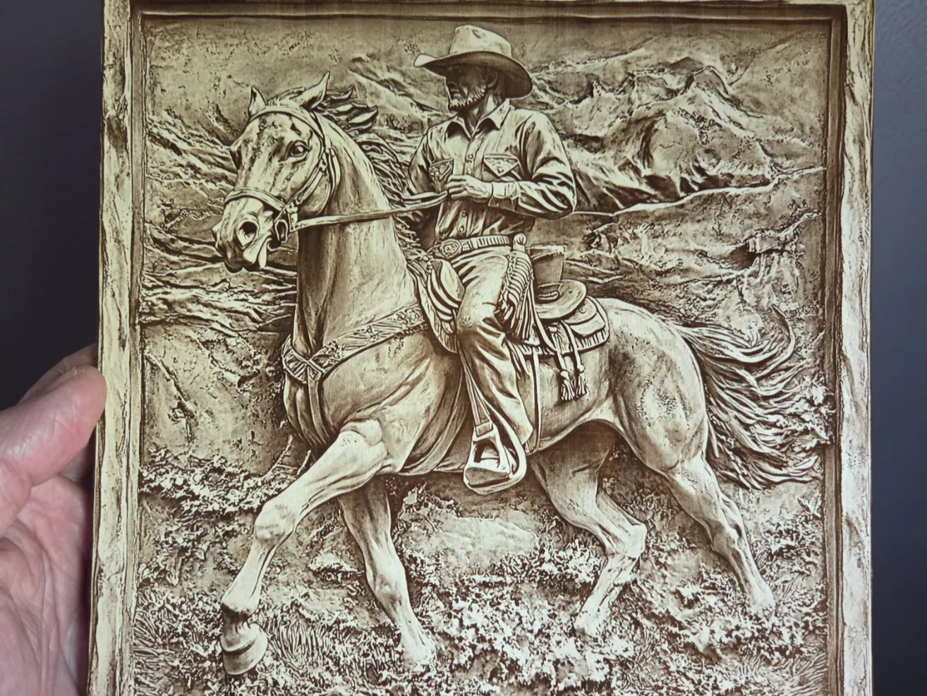 Western wall art featuring a cowboy riding a horse in a mountain landscape