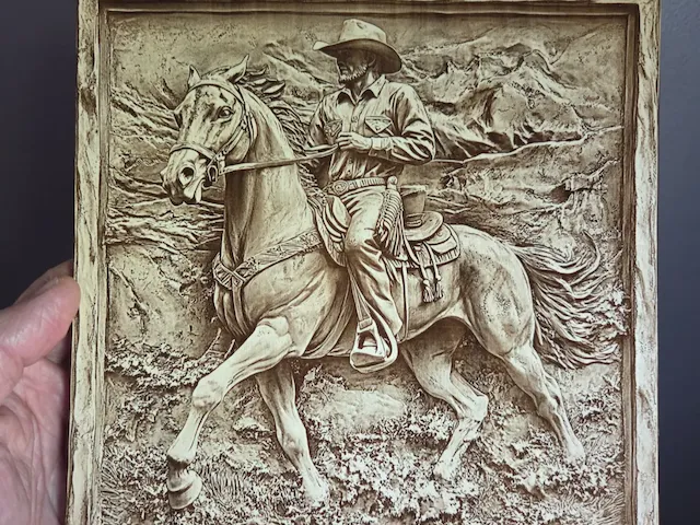 Western wall art featuring a cowboy riding a horse in a mountain landscape