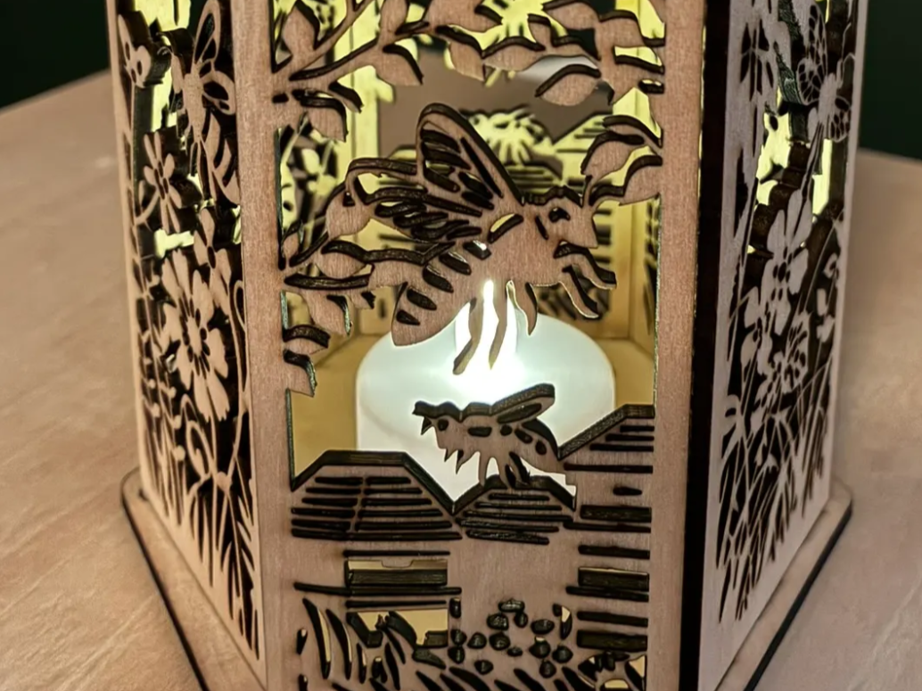 Close view of a wooden lantern with bee hive and flower cutouts lit by an LED garden light idea