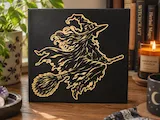 [Laser cut and engrave] Tableau noir avec illustration dorée d'une sorcière sur un balai
