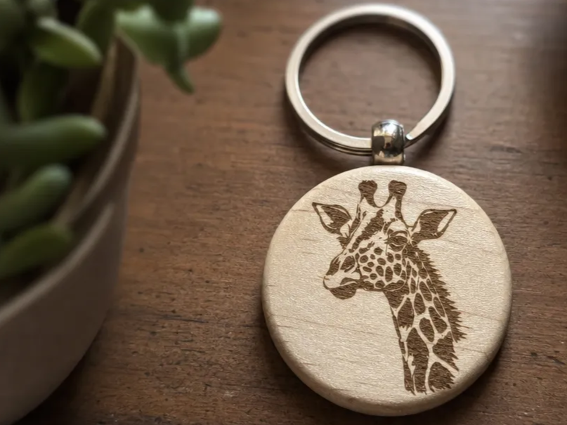 Round wooden keychain featuring a giraffe portrait