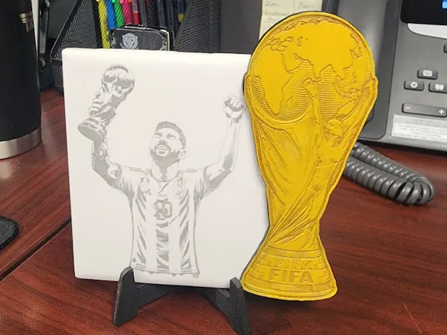 Lionel Messi holding World Cup trophy ceramic tile and gold trophy cutout