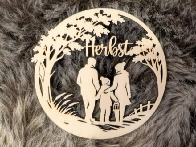 Runder Holzanhänger mit Herbstmotiv und Familie beim Laternenumzug