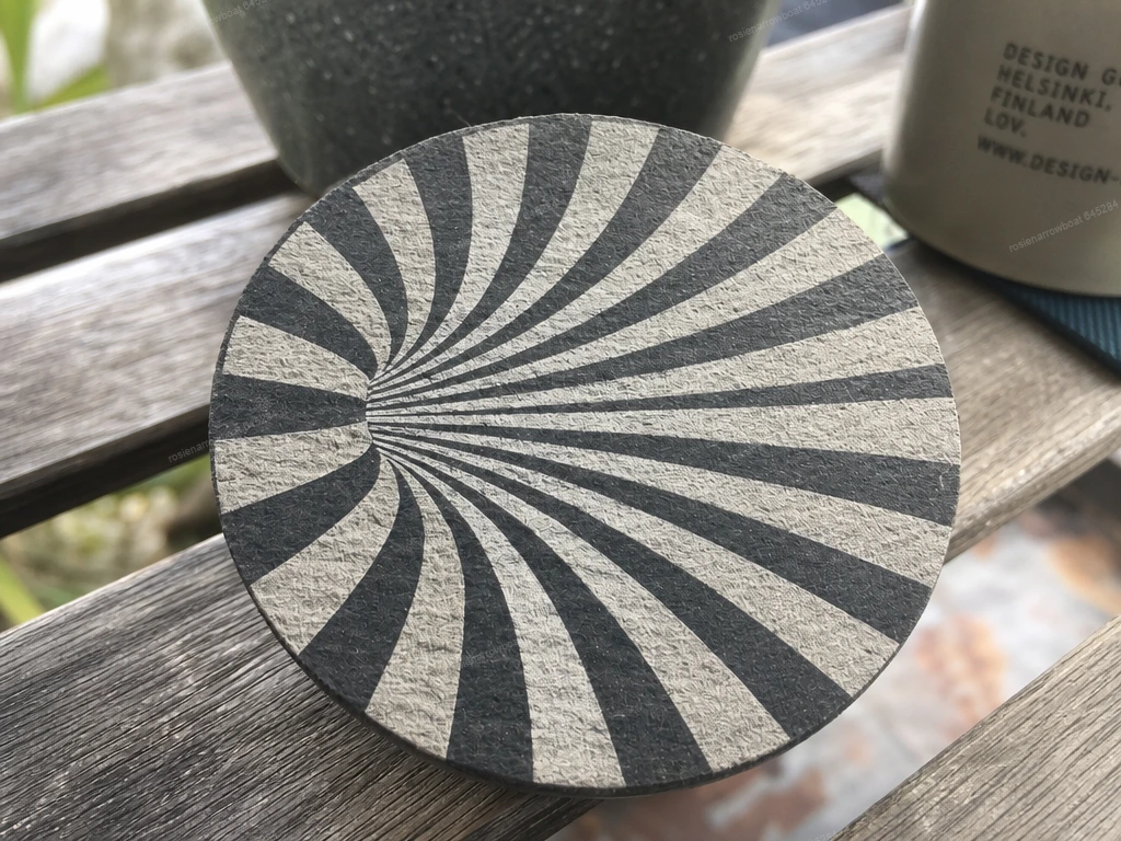 Round drink coaster with black and white optical illusion vortex pattern