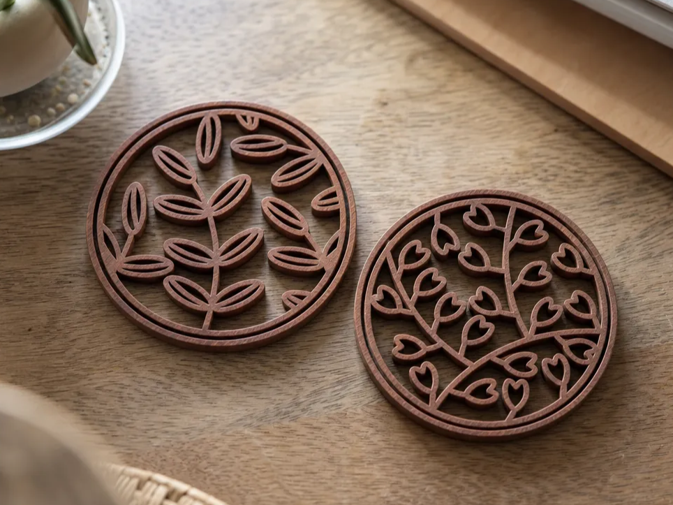 Round wooden coasters with intricate leaf and heart branch patterns