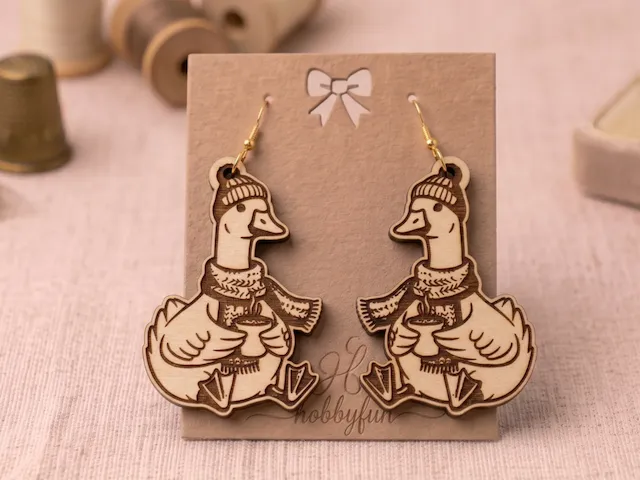 Wooden duck earrings wearing winter hats and scarves holding mugs
