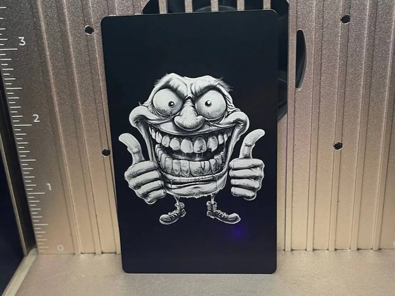 [Laser cut and engrave] Schwarze Metallkarte mit grinsendem Comic-Charakter