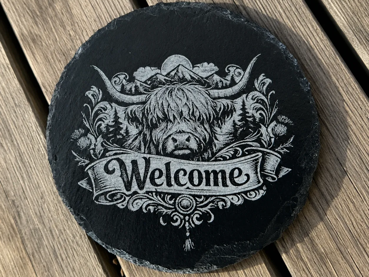 Round Slate Welcome Sign Featuring Highland Cow and Mountain Landscape